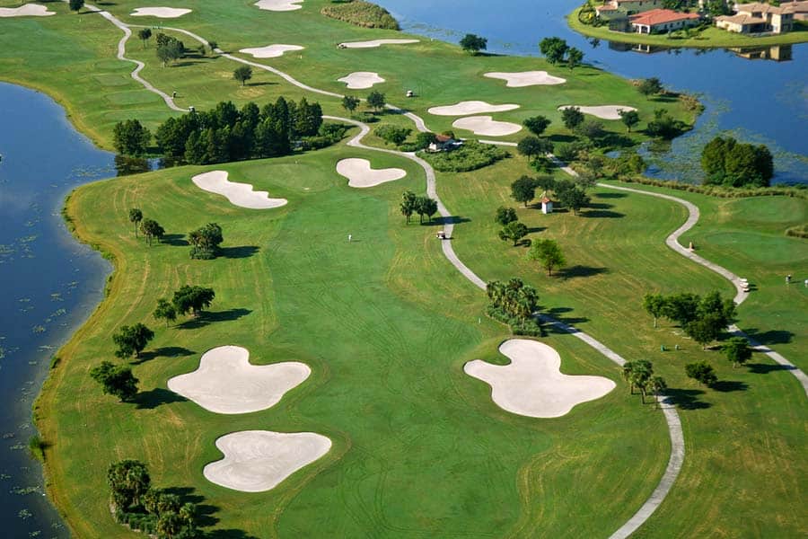 An ariel view of a golf course with sand bunkers and water bodies
