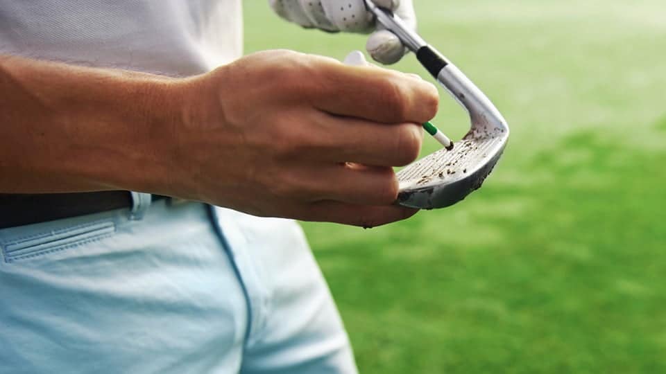 The golfer sharpens the grooves on the golf clubs with the help of groove club sharpener.