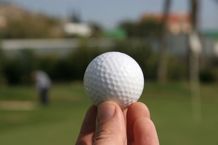 A close up of a white colored golf ball in the hand