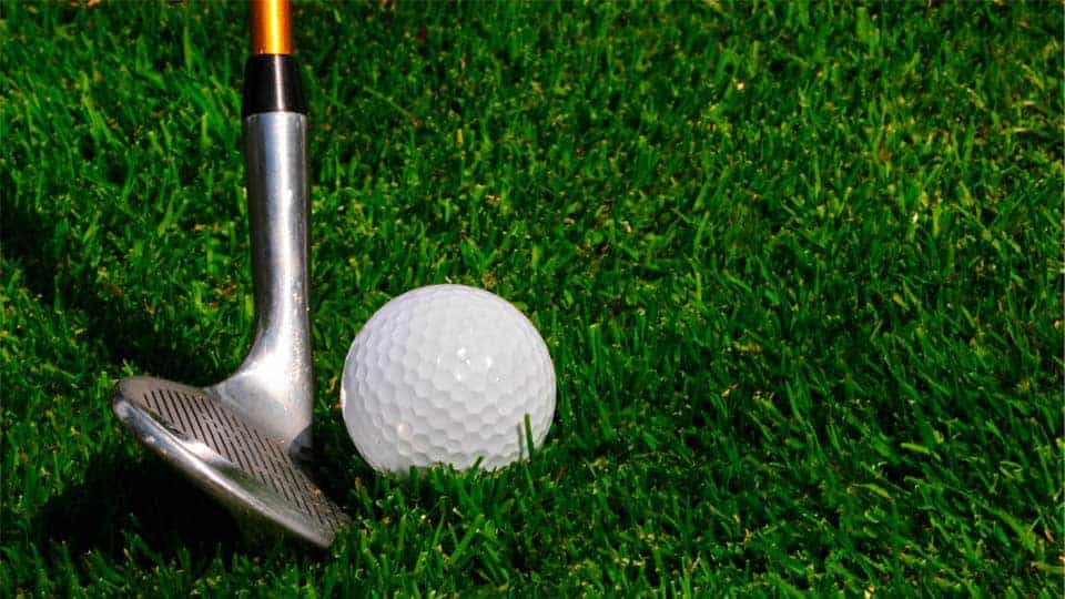 A pitching wedge is placed on the fairway with a golf ball