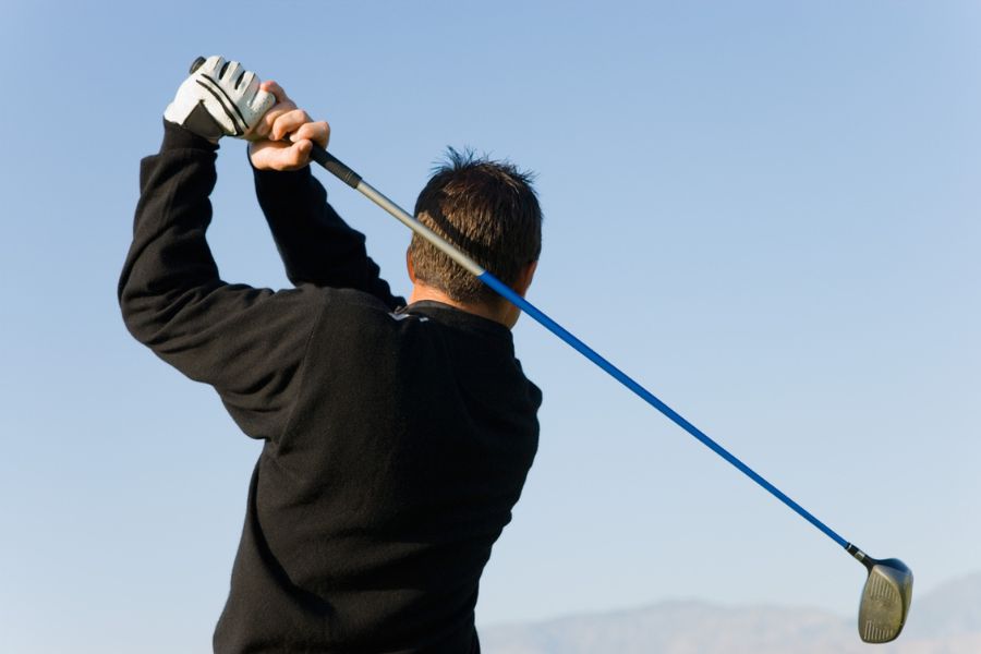 A golfer hits a shot with his driver.