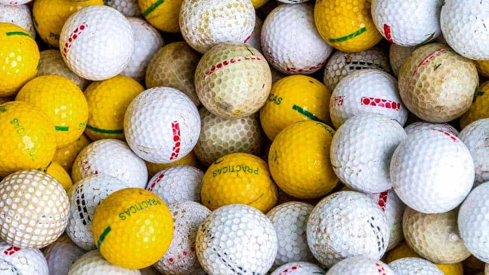 A basket full of dirty golf balls placed for cleaning.