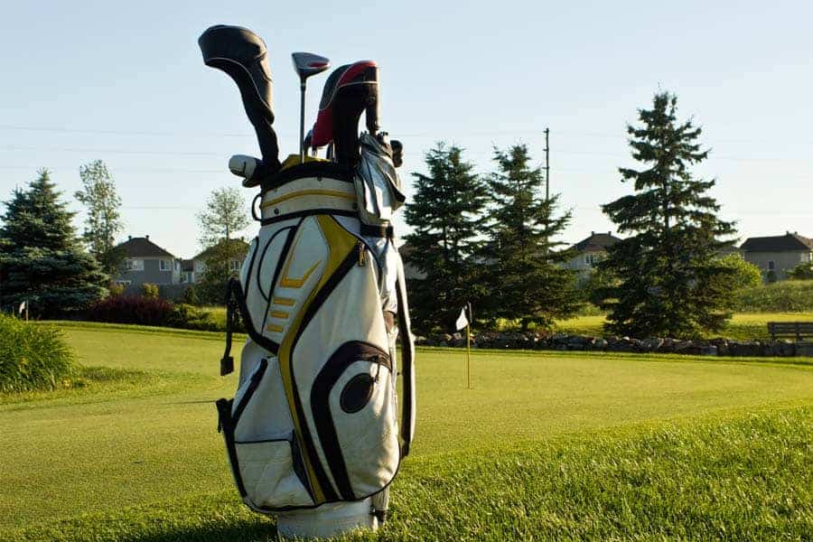 A golf bag filled with clubs is placed on the green course.