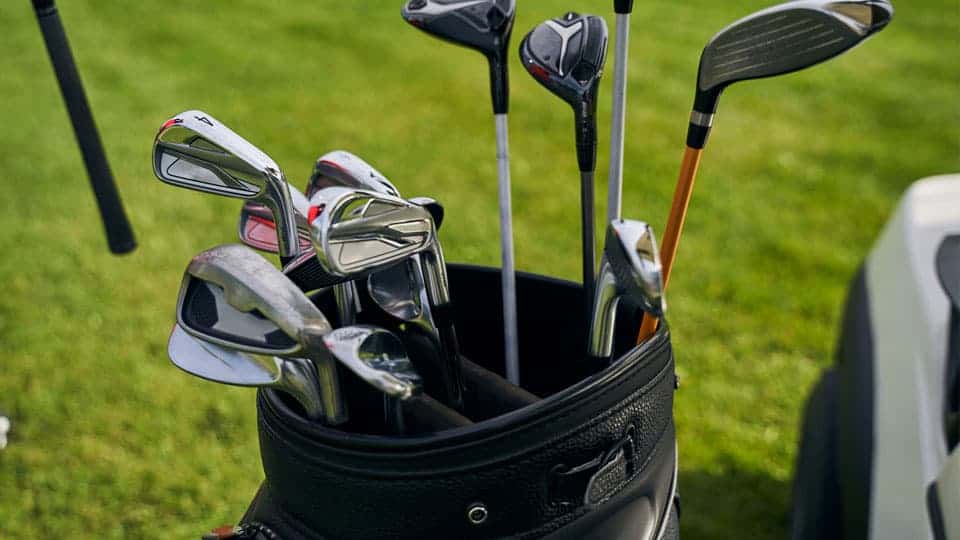 A total number of 14 clubs are placed in a golf bag over the course