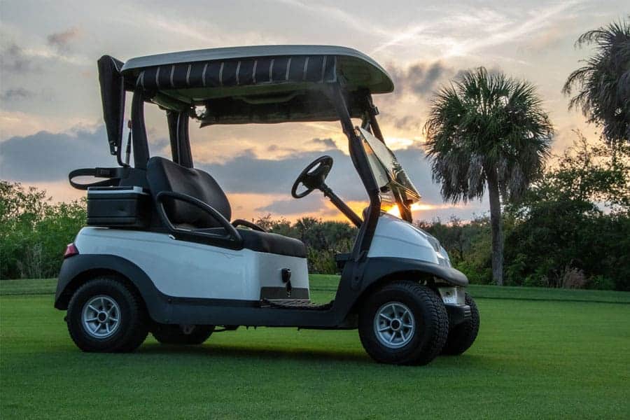 A golf cart is parked in a golf course on an evening