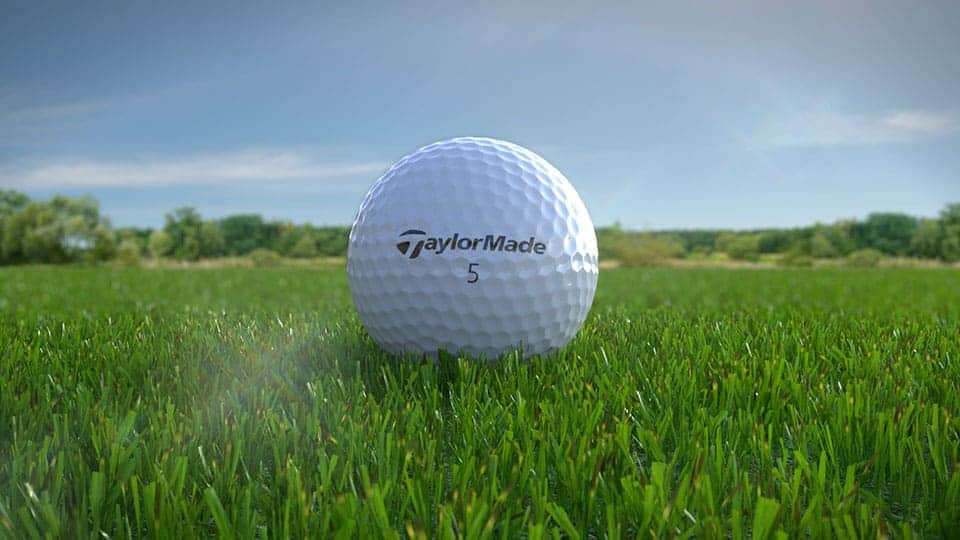 A taylormade burner golf ball labeled 5 is lying on a green in the golf course
