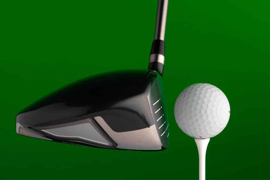 A close up of golf club with a golf ball placed ona tee near it.