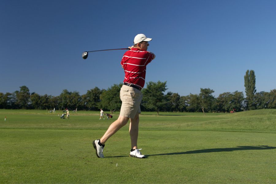 A golfer has hit the golf ball and observing how far it goes.