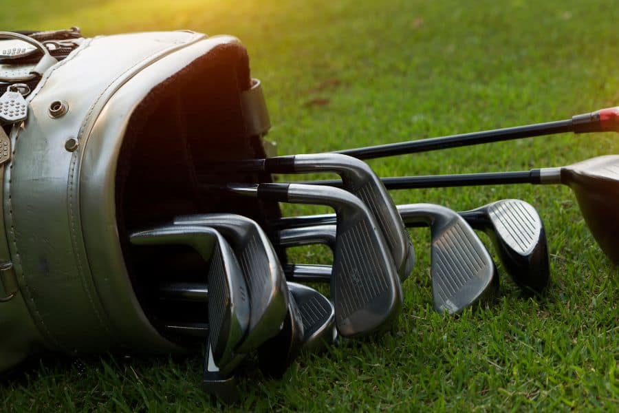 A golf bag with golf wedges is placed on the golf course
